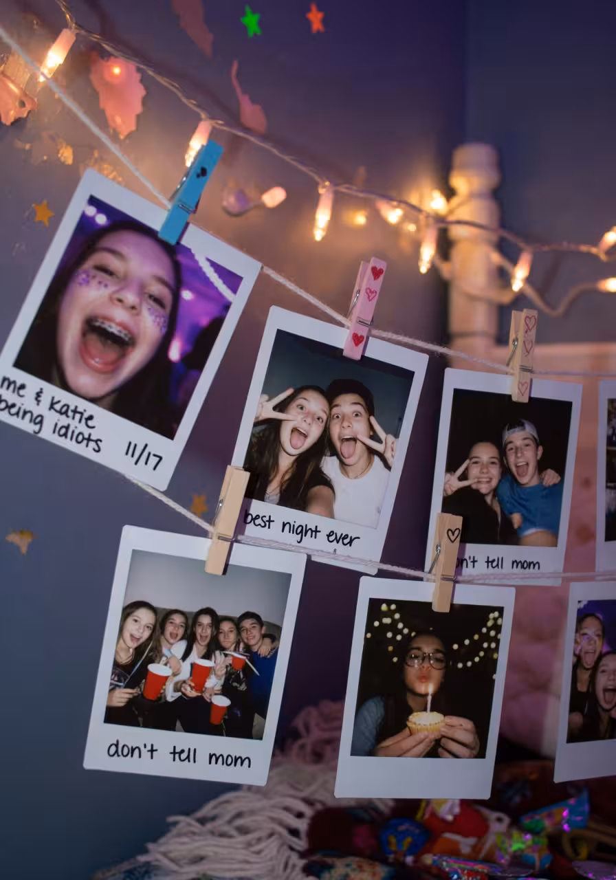 Instant photos hanging on string with clothespins and fairy lights at a candid teen holiday party